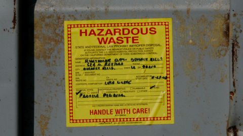 A close view of a label on one of several containers labeled as hazardous waste, presumably containing material scraped from the surface of an adjacent playground, is seen through a fence at Hawthorne Elementary School in Beverly Hills, Calif., Wednesday, Dec. 3, 2008. The playground was covered with AstroPlay, and the school district had it removed after discovering that the led level in its "root zone" was about 2 and 1/2 times the Environmental Protection Agency's standard. (AP Photo/Reed Saxon)