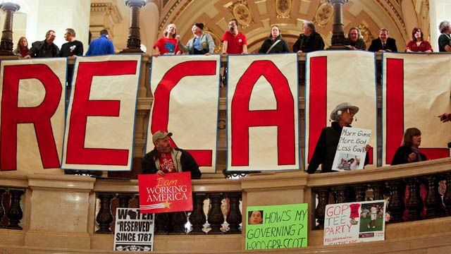 Protestors show off signs in the rotunda of the State Capitol prior to Gov. Scott Walker's state of the state address in Madison, Wis. January 2012. (AP Photo/Andy Manis)