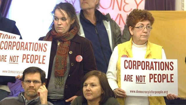 People hold signs during a rally in support of resolution calling for a constitutional amendment that says corporations are not people. January 2012. (AP Photo/Toby Talbot)