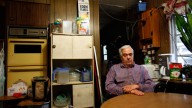 Bill Ricker, 74, sits at the kitchen table of his trailer home, in Hartford, Maine. Ricker, who has two college degrees, was injured in the late 1980s and hasn't worked since. September 2011. (AP Photo/Robert F. Bukaty)