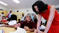 Michelle Rhee, right, talks to third grader Kmone Feeling during a visit at J.O. Wilson Elementary School on Aug. 23, 2010 in Washington. D.C. Rhee was D.C.'s public schools chancellor at the time. Mayor Adrian Fenty, back second left, and school principal Sheryl Warley, left, stand at the back. (AP Photo/Manuel Balce Ceneta)