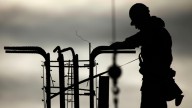 A construction worker silhouetted against the morning sky builds a planned shopping center in Philadelphia. (AP Photo/Matt Rourke)