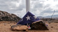 A flag sits at the base of a flag pole at the site where 19 firefighters died battling an Arizona wildfire on June 30th is shown Tuesday, July 23, 2013 in Yarnell, Ariz. As the fire grew out of control, the firefighters quickly worked to clear the area of scrub and brush hoping to endure the intense heat in their emergency shelters. (AP Photo/Matt York)