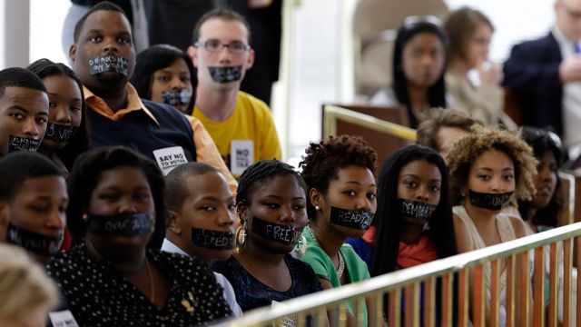 Members of North Carolina student chapters of the NAACP and opponents of voter ID legislation wear tape over their mouths while sitting silently in the gallery of the House chamber of the North Carolina General Assembly where lawmakers debated and voted on voter identification legislation in Raleigh, N.C., Wednesday, April 24, 2013. (AP Photo/Gerry Broome)