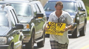 FILE - A man who did not wish to be identified, who lost his job two months ago after being hurt on the job, works to collect money for his family on a Miami street corner. (AP Photo/J Pat Carter, File)