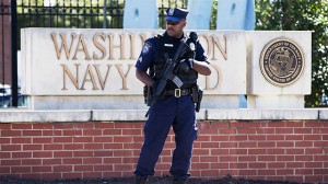 An armed officer who said he is with the Department of Defense, works near the gate at the Washington Navy Yard, closed to all but essential personnel the day after a gunman launched an attack inside the Washington Navy Yard on Monday. (AP Photo/Jacquelyn Martin)