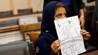 Nine-year-old Nabila Rehman holds a photo with a drawing she made depicting a drone strike that killed her grandmother, Tuesday, Oct. 29, 2013, during a news conference on Capitol Hill in Washington. (AP Photo/ Evan Vucci)
