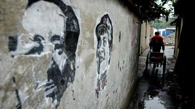 A man cycles past old portraits of late communist leader Mao Zedong on the wall of an alley in Shanghai, China. Worn out portraits and slogans from the 1960s and 1970s, when Mao's cult of personality was at its peak, can still be found across China. (AP Photo)