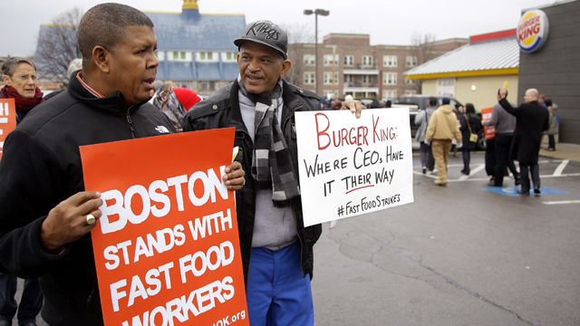 Pedro Rodriguez, right, talks with Andrus Reyes as they participate in a demonstration on a Burger King parking lot as part of a nationwide protest supporting higher wages for workers in the fast-food industry and other minimum wage jobs in Boston, Thursday, Dec. 5, 2013. (AP Photo/Stephan Savoia)