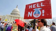 A protestor holds up a sign that says 'Hell No Obamacare' at a rally