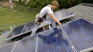 Terrence Brand installs solar panels donated by the Green Mountain Energy Company on the first Houston Habitat for Humanity home equipped with a solar array on Friday, May 9, 2003, in Houston. (AP Photo/Brett Coomer)