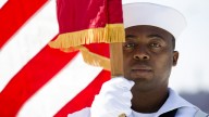 Seaman Daniel Odoi of the Navy Operational Support Center of New York City presents the American flag during a Memorial Day wreath laying at the Franklin D. Roosevelt Four Freedoms Park on Roosevelt Island, Monday, May 27, 2013, in New York. (AP Photo/John Minchillo)