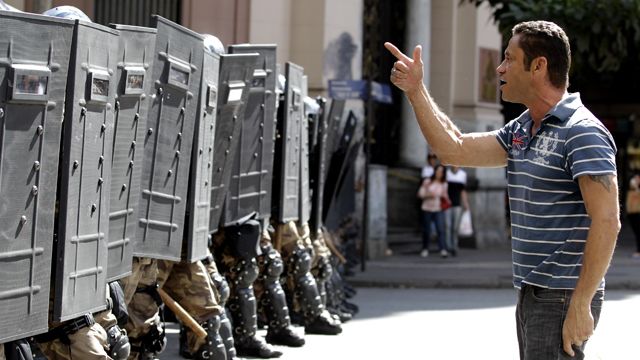 A demonstrator argues with police lined up during a protest against the World Cup in Belo Horizonte, Brazil, Saturday, June 14, 2014. Anti-World Cup demonstrators are demanding better public services and protesting the money spent on the international soccer tournament. (AP Photo/Bruno Magalhaes)
