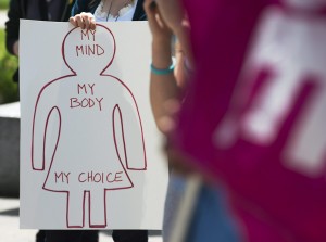 A demonstrator holds a sign, as they campaign for improved access to abortion in Canada, Thursday, May 29, 2014, during a gathering at Victoria Park on the one-year anniversary of the death of Dr. Henry Morgentaler in Halifax, Nova Scotia. Morgentaler, the Abortion rights activist, helped overturn Canada's abortion law. (AP Photo/The Canadian Press, Andrew Vaughan)