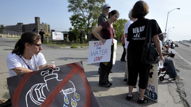 Rachel Fentin, left, 23, of Detroit, holds a sign denouncing water shutoffs as members of The People’s Water Board Coalition protest Detroit’s cutting off the water supply to some residents, in Detroit on Friday, July 18, 2014.
