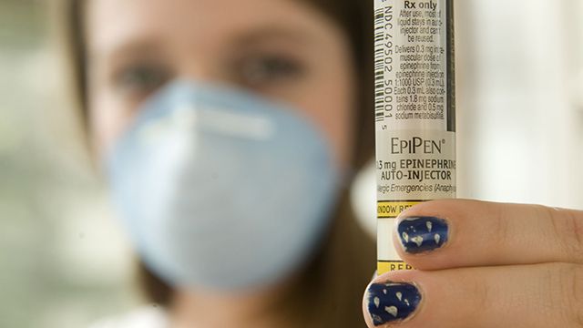 Danielle Davis, a West Virginia high school student with severe nut allergies, displays an EpiPen and wears a protective mask. (AP Photo/Bob Bird)