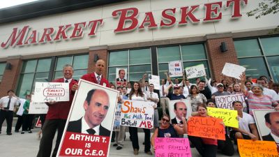 Market Basket assistant managers Mike Forsyth, left, and John Surprenant, second from left, hold signs while posing with employees in Haverhill, Mass., Thursday, July 24, 2014, in a show of support for "Artie T." Arthur T. Demoulas, the former chief executive of the Market Basket supermarket chain whose ouster has led to employee protests, customer boycotts and empty shelves, says he wants to buy the entire company. (AP Photo)