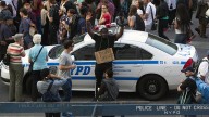Holding a camera and wearing a âDonât Shootâ sign, Antoine Wallace raises his hands while leaning against a New York City police car during a protest march in New York, Thursday, Aug. 14, 2014. (AP Photo/Michael R. Sisak)