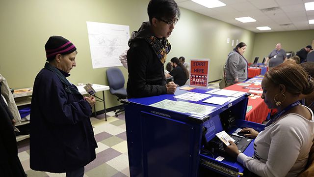 In this photo, voters stand in line to have an election official check their photo identification at an early voting polling site, in Austin, Texas, Feb. 26, 2014. (AP Photo/Eric Gay)