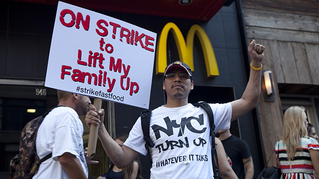On September 4, 2014, a protester holding a sign that says "On Strike to Lift My Family Up" was in front of McDonald restaurant near Columbus Circle. In New York City, 21 fast food workers were arrested that day in an organized nationwide strike to demand $15-an-hour and a union. (Photo: Charina Nadura/ Moyers & Company)