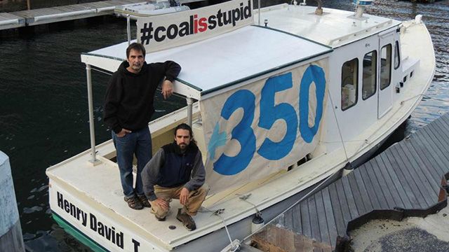 Ken Ward (left) and Jay O’Hara on the boat they used to block the delivery of 40,000 tons of coal to a power plant in Somerset. (Photo: 350Mass)