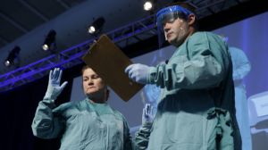 Nurse Barbara Smith, left, and Dr. Bryan Christensen demonstrate the proper way for health care workers to use personal protective equipment when dealing with Ebola during an education session in New York, Tuesday, Oct. 21, 2014. Thousands of participants, mostly health care workers, attended the session to review basic facts about Ebola and updated guidelines for protection against its spread. (AP Photo/Seth Wenig)