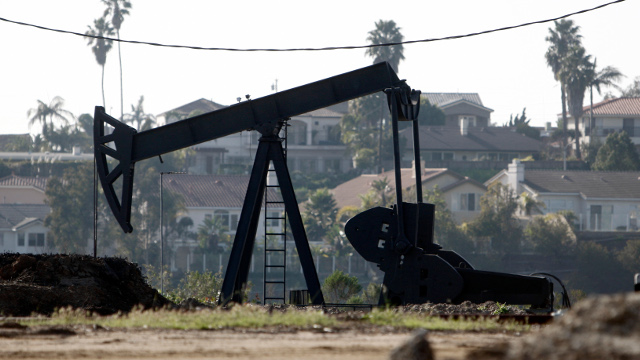 A rig pumps oil in the unincorporated Windsor Hills area of Los Angeles adjacent to homes Friday, Feb. 12, 2010.  (AP Photo/Reed Saxon)