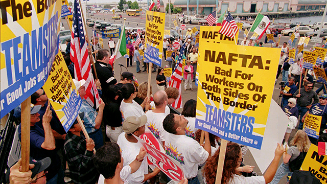 About 200 Teamsters raise their signs while protesting new NAFTA trucking regulations outside the Holiday Inn in San Diego Tuesday June 18, 1996. The Teamsters protested a meeting on the North American Free Trade Agreement against lifting a ban on Mexican trucks being allowed on US roads and highways. (AP Photo/Denis Poroy)