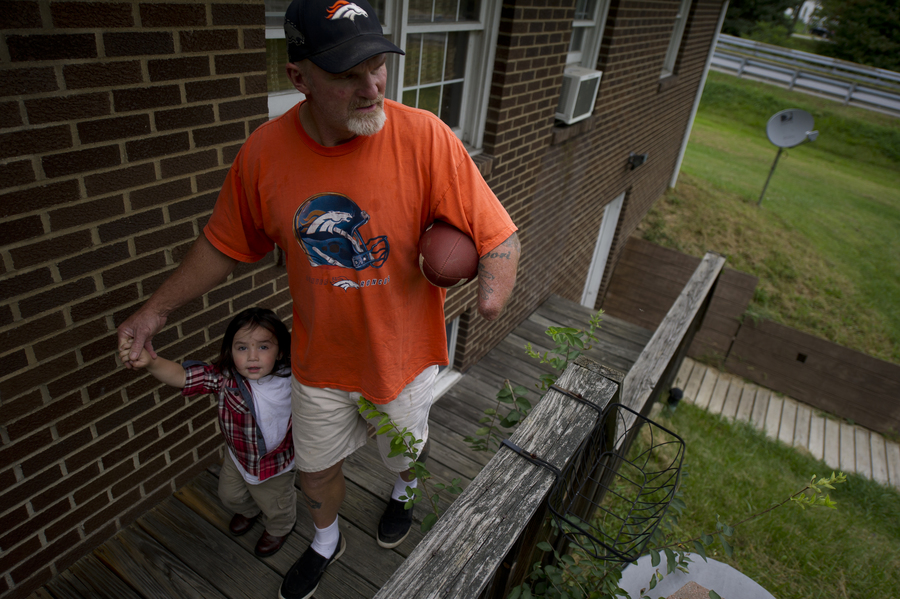 Despite the setbacks he’s faced with his injury and workers’ comp, Dennis Whedbee has tried to maintain an active life, waking early for yard sales, cooking homemade spaghetti sauce and throwing a football with his grandsons. Here, he walks his grandson Haven, 2, back inside their home in Homer City, Pennsylvania. (Jeff Swensen for ProPublica)