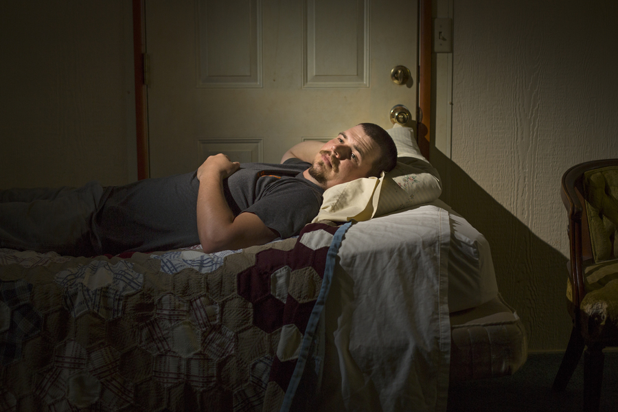 John Coffell lies on a bed in his grandmother’s living room outside Hulen, Oklahoma as his sons watched cartoons, and his daughter, in pigtails and an orange tutu, bounced on a ball nearby. (Brett Deering/AP for ProPublica)