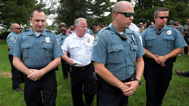 Ferguson Police Chief Tom Jackson is surrounded by his officers as he leaves a news conference in Forestwood Park on Friday, Aug. 15, 2014. Jackson took questions in the quiet park after earlier identifying Darren Wilson as the officer who shot Michael Brown. (AP Photo/St. Louis Post-Dispatch, Robert Cohen)