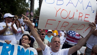 From left, Fatima Berrahal and Educardo Burkhart, of West Palm Beach, listen to billionaire Donald Trump as he addresses a crowd at the 2011 Palm Beach County Tax Day Tea Party on April 16, 2011 at Sanborn Square in Boca Raton, Florida. (Photo by John W. Adkisson/Getty Images)