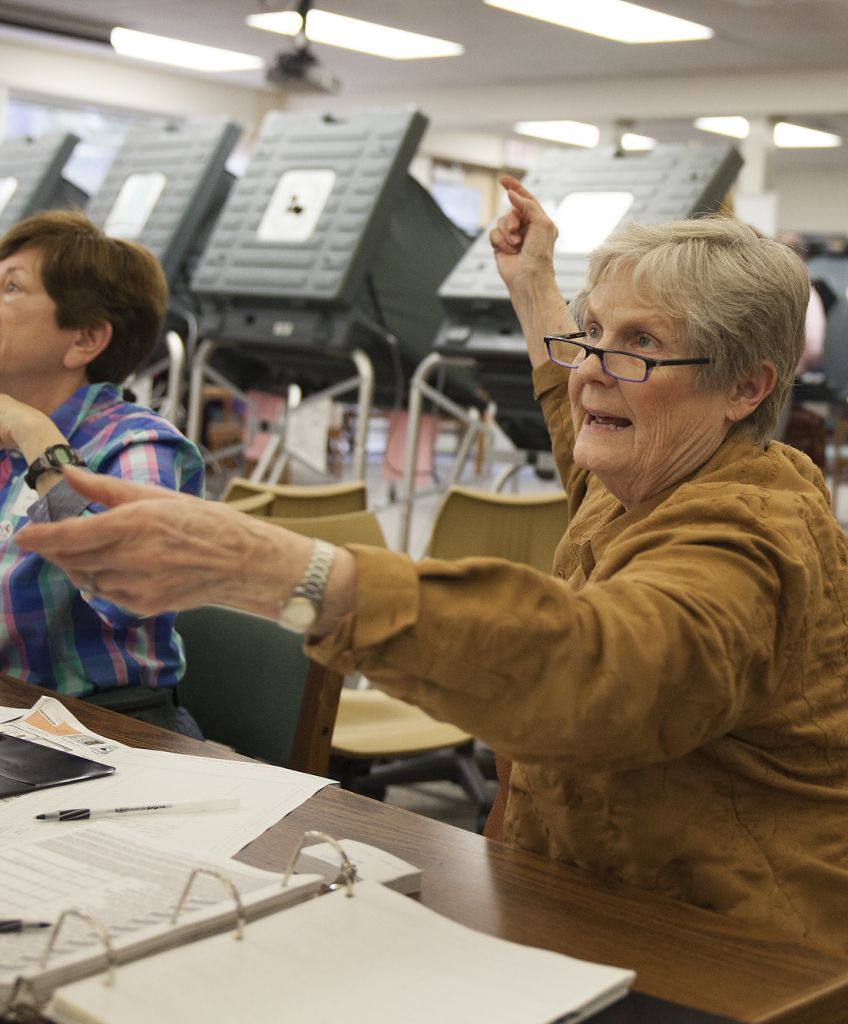 Ann Moss checks a voter's ID before signing her in to vote at Hunters Creek Elementary School in Houston. (Photo by Lucian Perkins /for The Washington Post via Getty Images)