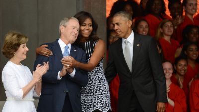 First lady Michelle Obama embraces former President George W. Bush, accompanied by his wife, former first lady Laura Bush, at the dedication of the National Museum of African American History and Culture in Washington, DC. (Photo by Astrid Riecken/Getty Images)