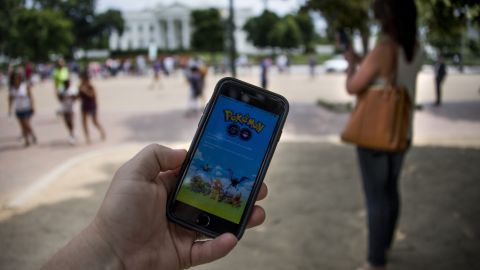 A tourist holding cell phone with Pokemon Go game in front of White House.