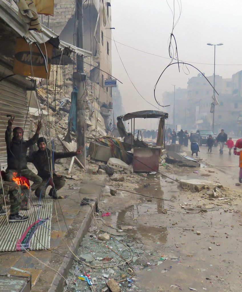 Syrian pro-regime fighters gesture as residents, fleeing violence, arrive in Aleppo's Fardos neighborhood on December 13, 2016, after regime troops retook the area from rebel fighters. (Photo: STRINGER/AFP/Getty Images)