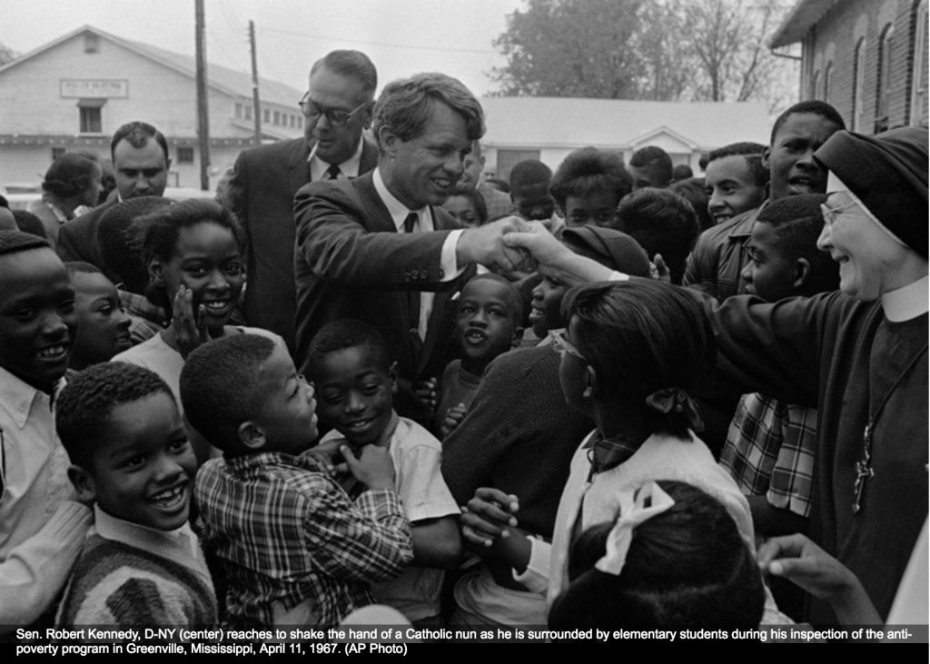 Sen. Robert Kennedy (D-NY) (center) reaches to shake the hand of a Catholic nun as he is surrounded by elementary school children during his inspection of an anti-poverty program in Greenville, Mississippi on April 11, 1967. (AP Photo)