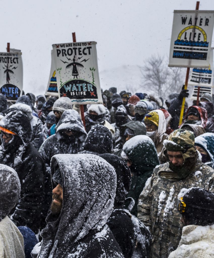 Winter arrived in Standing Rock at the Oceti Sakowin Camp in North Dakota on Dec. 5, 2016, the day after the Army Corps of Engineers denied the easement needed to build the pipeline. Despite driving snow and 40-plus mile an hour wind a group of more than 700 veterans and water protectors marched toward the barricade on highway 1806. (Photo by Michael Nigro/Pacific Press/LightRocket via Getty Images)