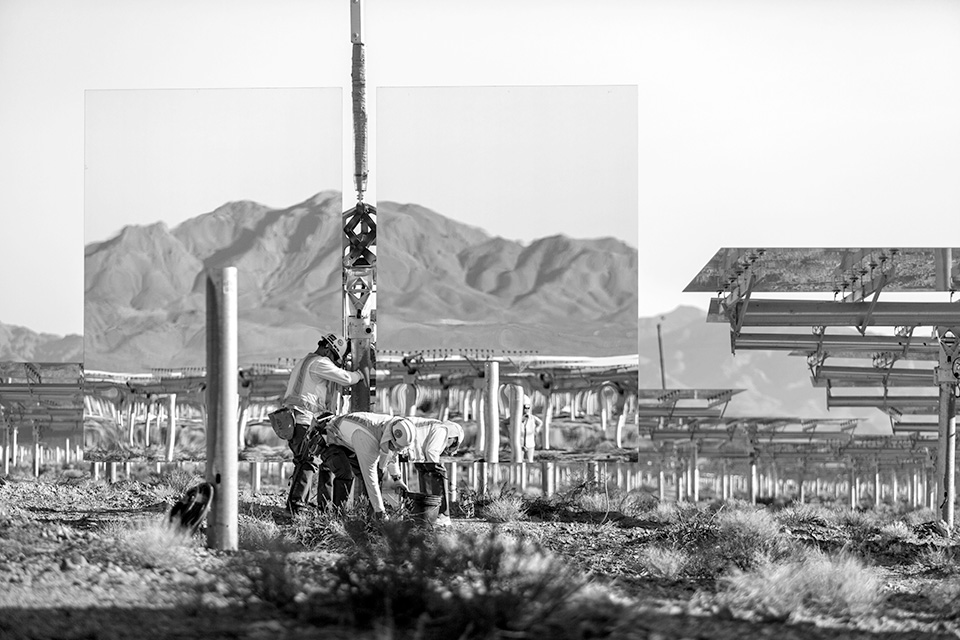 Installing a heliostat for Unit 1, with mountains reflected in its mirrors, at Ivanpah Solar in the Mojave Desert of California. (Photo by Jamey Stilings)