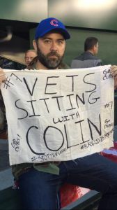 Rory Fanning sitting in solidarity with Colin Kaepernick at a Chicago Cubs baseball game in 2016. (Photo courtesy of Rory Fanning)