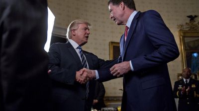 President Donald Trump (C) shakes hands with James Comey, director of the Federal Bureau of Investigation (FBI), during an Inaugural Law Enforcement Officers and First Responders Reception in the Blue Room of the White House on January 22, 2017 in Washington, DC. (Photo by Andrew Harrer-Pool/Getty Images)