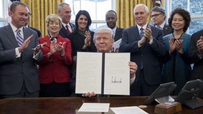 President Donald Trump shows an executive order entitled, "Comprehensive Plan for Reorganizing the Executive Branch" after signing it beside members of his Cabinet in the Oval Office on March 13, 2017. (Photo by Michael Reynolds-Pool/Getty Images)