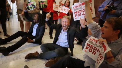 Demonstrators from Texas sit on the ground and chant, "Kill the bill, kill the bill," outside the offices of Sen. Ted Cruz (R-TX) while protesting against health care reform legislation in the Russell Senate Office Building in Washington, DC on July 10, 2017. More than 100 people from across the country were arrested during the protest that was organized by Housing Works and Center for Popular Democracy. (Photo by Chip Somodevilla/Getty Images)