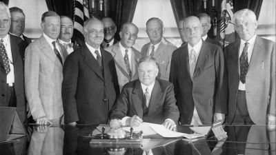 President Hoover signing the Farm-Relief Bill at the White House on June 15, 1929, providing for a $500,000,000 revolving fund to stabilize agriculture and stimulate cooperative marketing. Joining him are (left to right): Sen. Charles L. McNary (R-OR), Vice President Charles Curtis, Speaker of the House Nicholas Longworth (R-OH) and Rep. Gilbert N. Haugen (R-IA). (Photo by Harris & Ewing, Library of Congress Prints and Photographs Division)